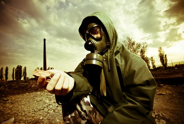 stock image Scientist with gas mask examining rock in destroyed territory after explosi