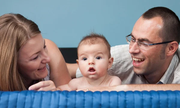 Schöne junge Familie mit Baby im Schlafzimmer — Stockfoto
