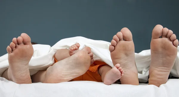 Δέντρα ζευγάρια ποδιών της ευτυχισμένης οικογένειας στο κρεβάτι - πατέρας, μητέρα και μωρό — Φωτογραφία Αρχείου