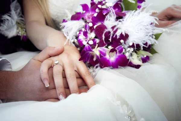 Mãos e anéis no buquê de casamento — Fotografia de Stock