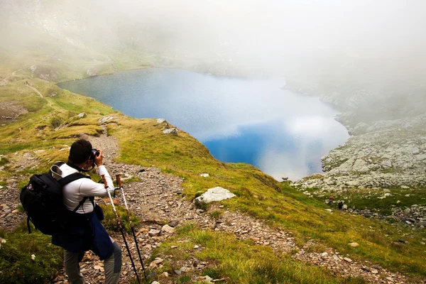 Senderista tomando fotos en el lago Capra en las montañas de Fagaras, Rumania — Foto de Stock