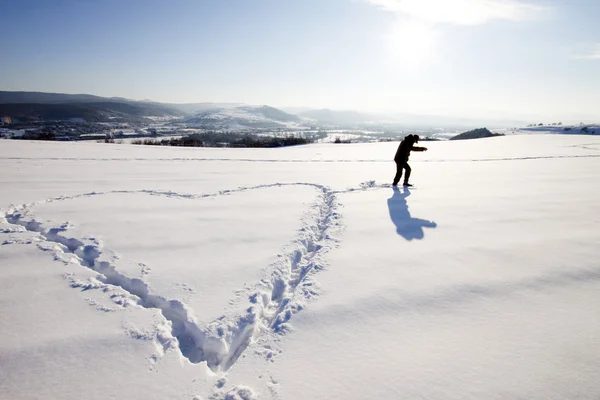 Muž dělat velký sníh znamení ve sněhu — Stock fotografie