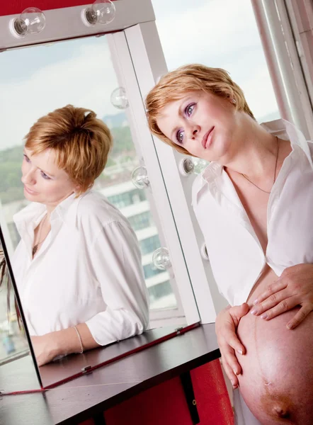 Beautiful pregnant woman daydreaming in front of a mirror — Stock Photo, Image