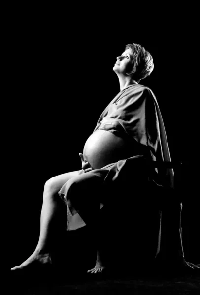 9 meses de mulher grávida sentada na cadeira e olhando para cima em preto e branco — Fotografia de Stock