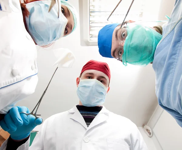 Cirurgiões segurando instrumentos médicos nas mãos e olhando para o paciente — Fotografia de Stock