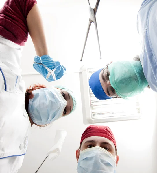 Хірурги тримають медичні інструменти в руках і дивляться на пацієнта — стокове фото