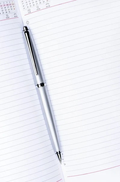 Silver pen on notebook vertical — Stock Photo, Image