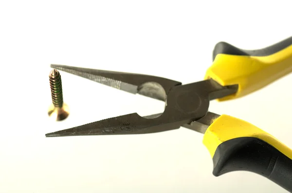 Black and yellow pliers and screw — Stock Photo, Image