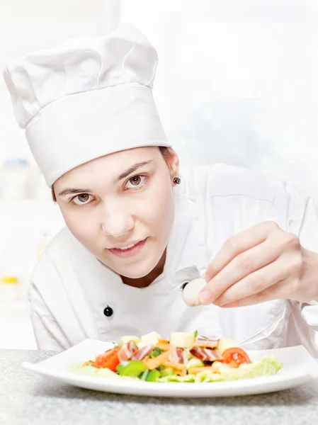 Молодий шеф-кухар прикрашає смачний салат — стокове фото