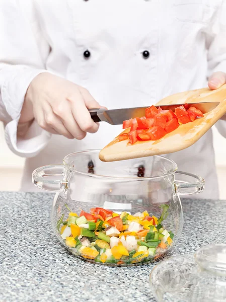 Stock image Chef adds chopped tomatoes in a glass bowl