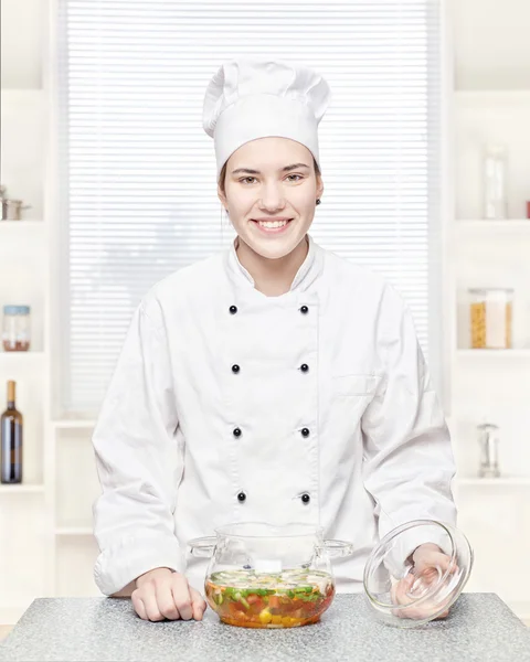 Chef with a soup of vegetables in a glass pot — Stock Photo, Image