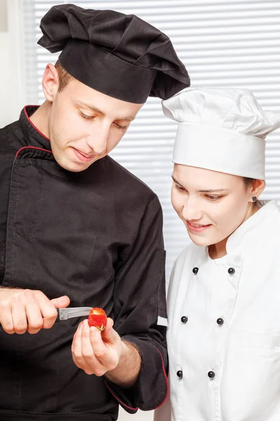 Senior chef-kok onderwijst jonge chef-kok voor het decoreren van vruchten — Stockfoto