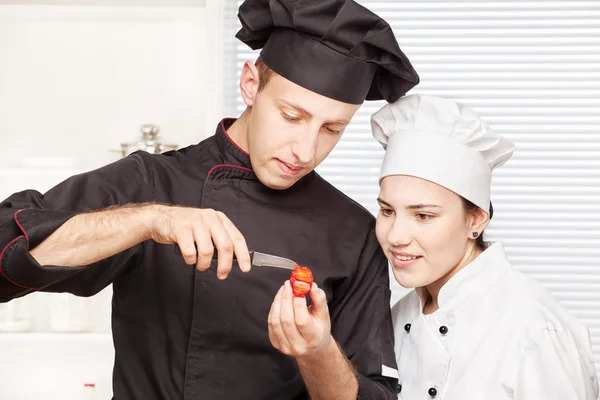Senior chef teaches young chef to decorate fruit — Stock Photo, Image