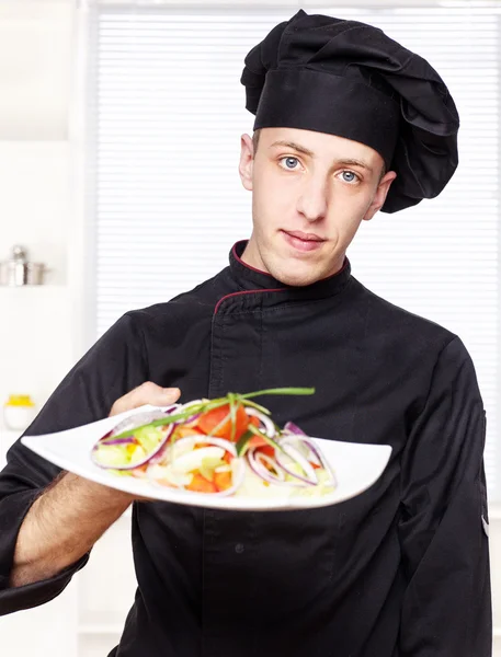 Chef in black uniform offer salad — Stock Photo, Image