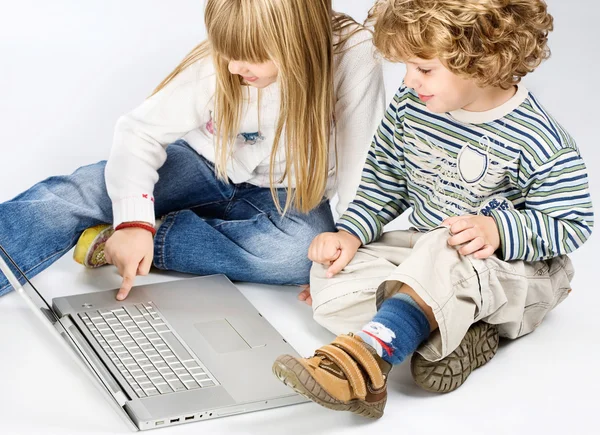 Menina e menino assentos perto do laptop — Fotografia de Stock
