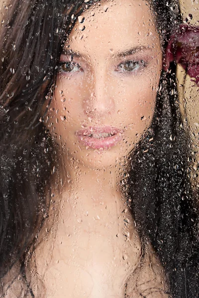 Vrouw gezicht achter glas vol water drops — Stockfoto