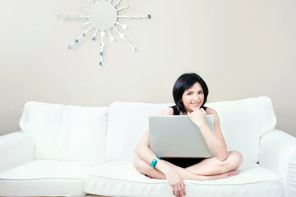 Mädchen auf weißem Sofa mit Laptop — Stockfoto