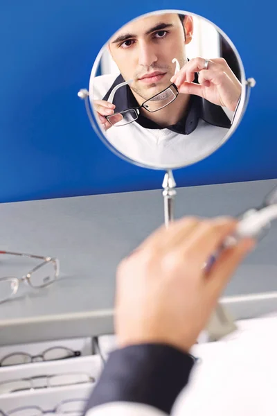 Viso di un uomo in uno specchio mentre prova gli occhiali — Foto Stock