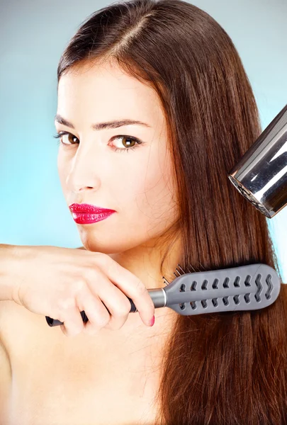 Mujer con pelo largo sosteniendo secador de pelo y peine —  Fotos de Stock