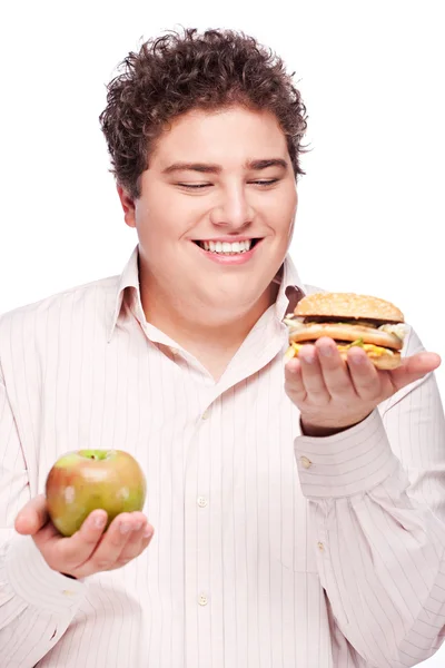 Hombre regordete sosteniendo manzana y hamburguesa —  Fotos de Stock