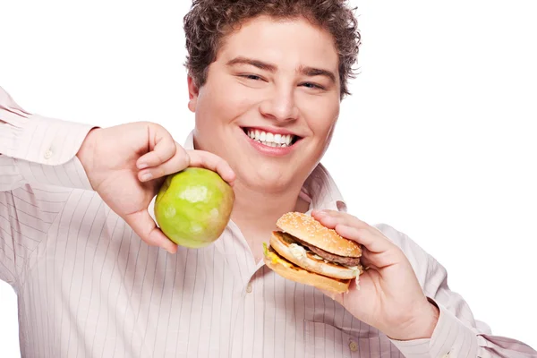 Obtloustlý muž drží jablko a hamburger — Stock fotografie