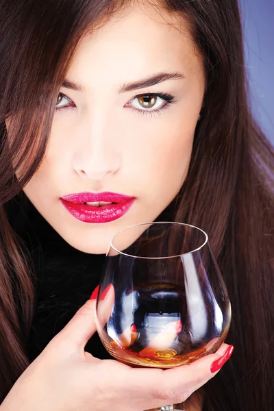 Woman with pelt, holding glass of brandy — Stock Photo, Image