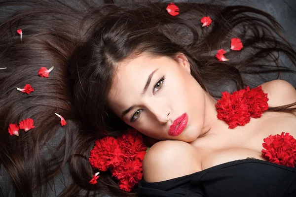 Woman with long hair and red carnations — Stock Photo, Image