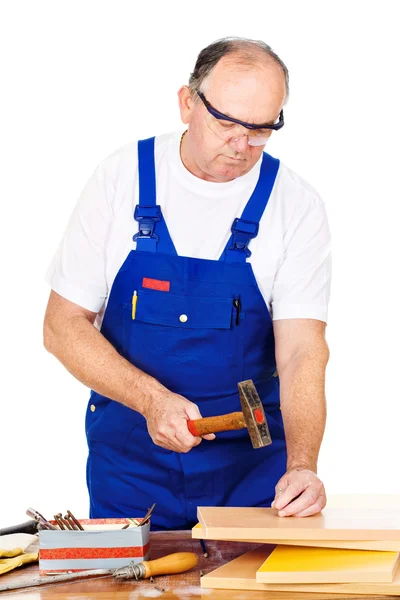 Middle age worker hammering nails in board — Stock Photo, Image