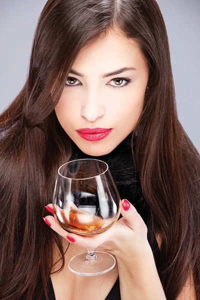 Woman with pelt holding glass of brandy — Stock Photo, Image