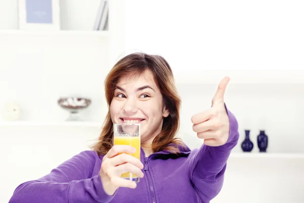 Boldog tinédzser lány italok narancslé otthon — Stock Fotó