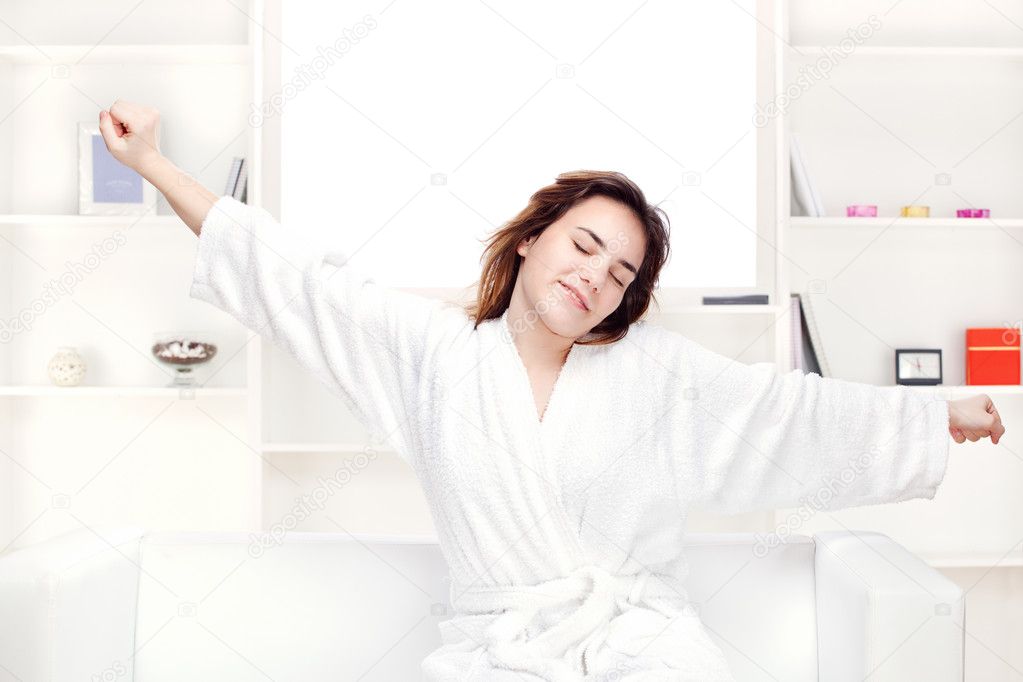 Girl in bathrobe at home stretching arms
