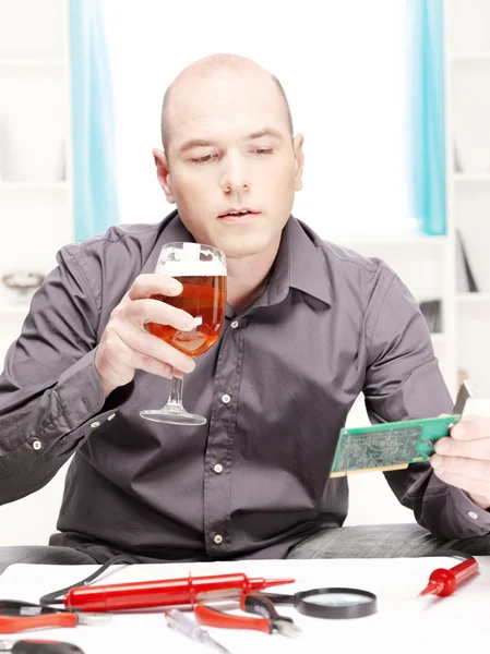 Man with beer doing minor electronic repair at home — Stock Photo, Image