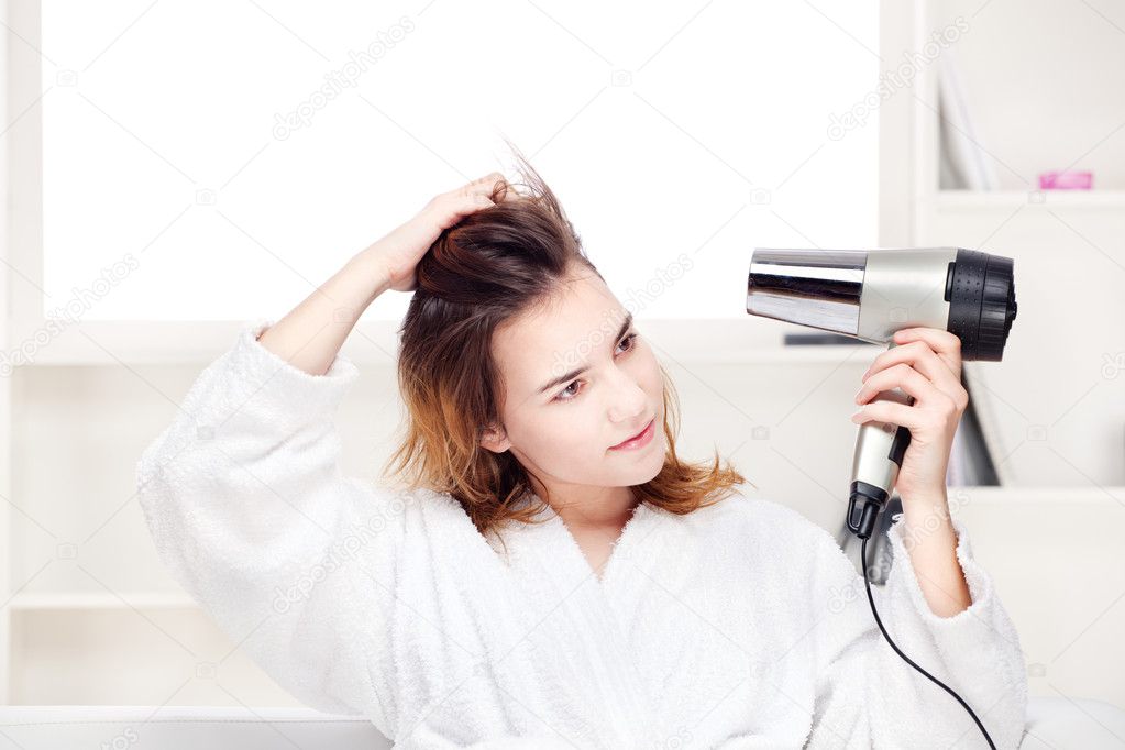 Girl drying her hair at home