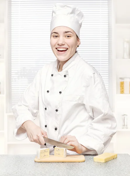 Jonge chef-kok snijden blauwe kaas in kitchenn — Stockfoto