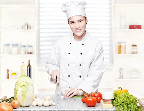Jonge chef-kok snijden uien in keuken — Stockfoto