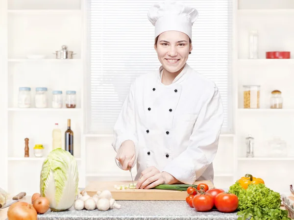 Chef feminino cortando cebolas na tábua de corte na cozinha — Fotografia de Stock