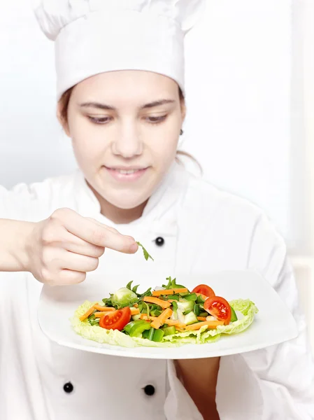 Young chef decorating delicious salad — Stock Photo, Image