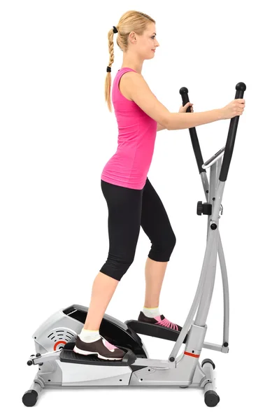 Jonge vrouw doen oefeningen op elliptische trainer — Stockfoto