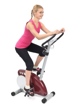 Young woman doing indoor biking exercise clipart
