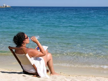 Woman drinking water on the beach clipart