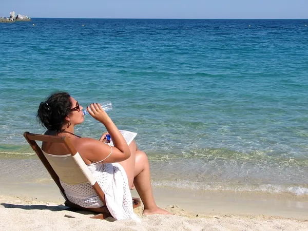 女性はビーチで水を飲む — ストック写真