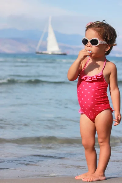 Chica con piruleta en la playa — Foto de Stock