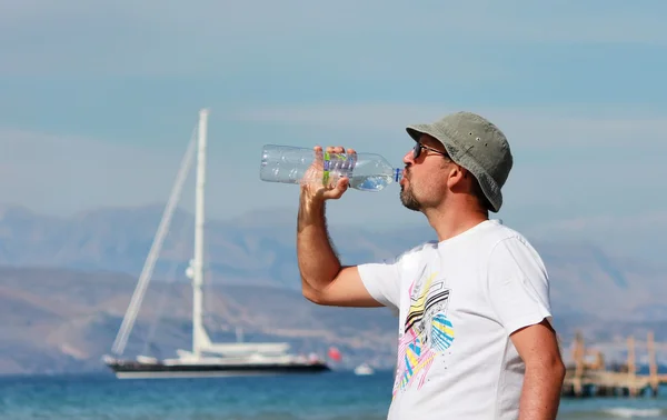 Mann trinkt Wasser auf dem Meer — Stockfoto