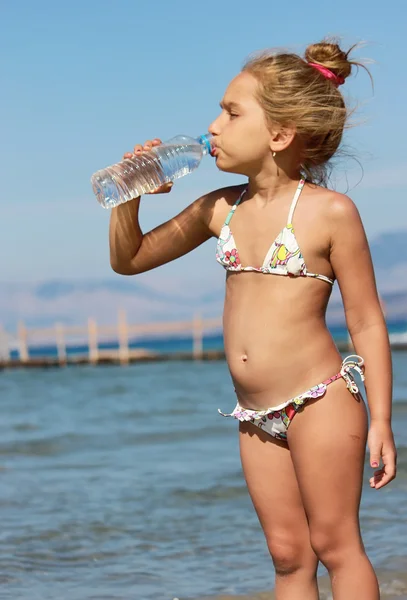 stock image Girl dinking water on the beach