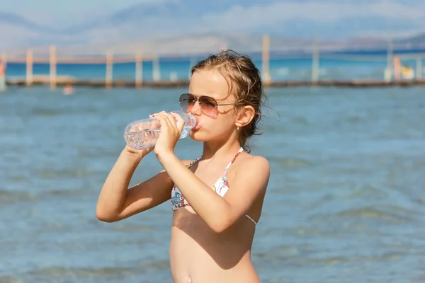 Mädchen, das Wasser am Strand isst — Stockfoto