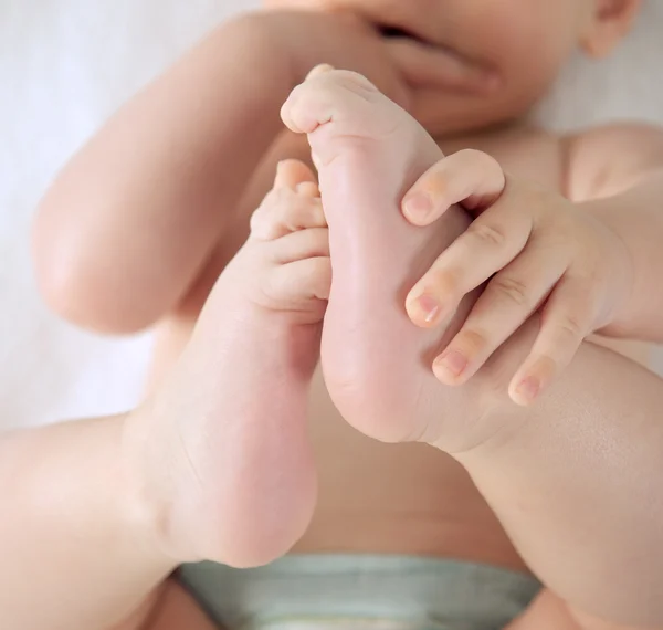 Baby houden zijn voeten — Stockfoto