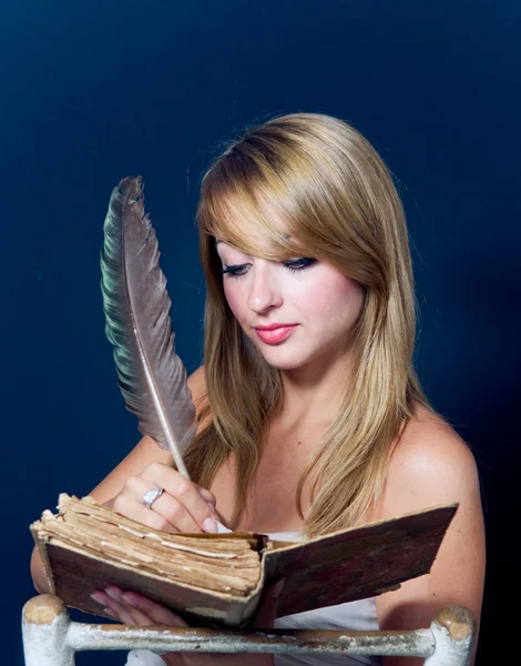 Девушка, пишущая в старой книге — стоковое фото