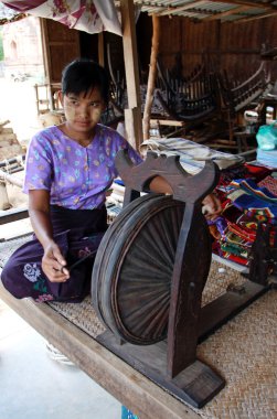 Young myanmar girl working at spinning wheel clipart