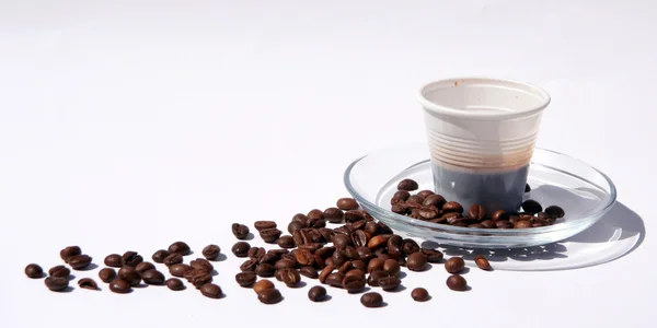 Plastic cup and coffee beans, break shot — Stock Photo, Image
