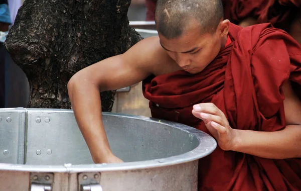 Mönch nimmt Reis aus einer großen Pfanne, Myanmar — Stockfoto